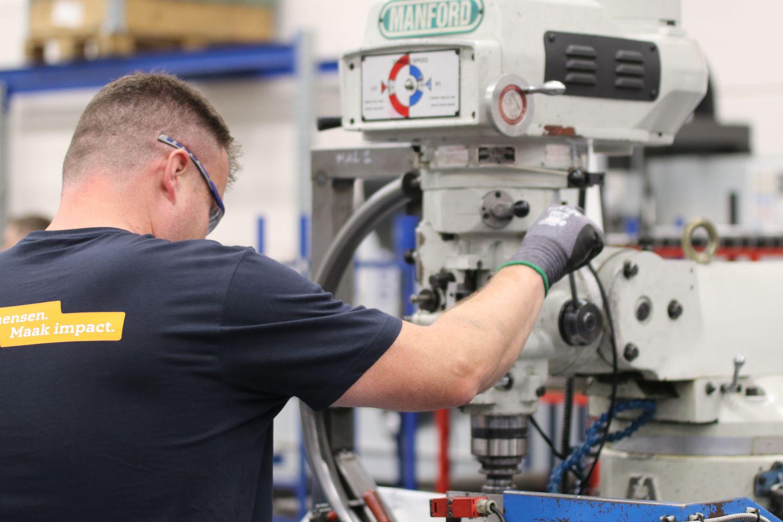 Machinist setting up a turret milling machine on a workshop floor