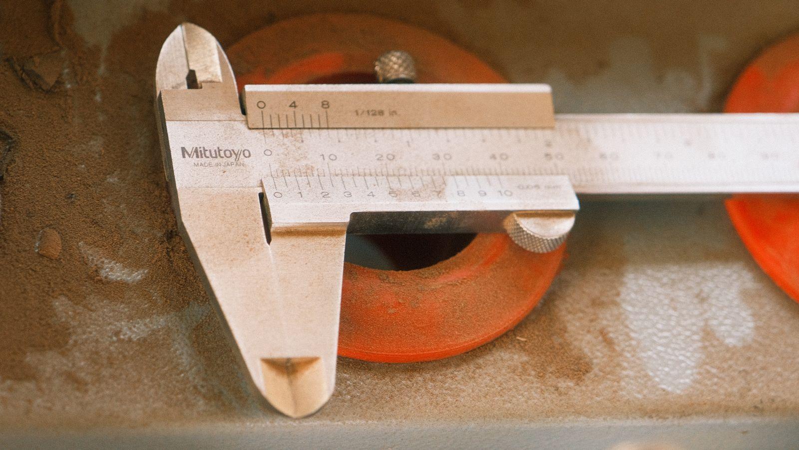 Vernier caliper checking the dimensions of a coated ring component on a workbench