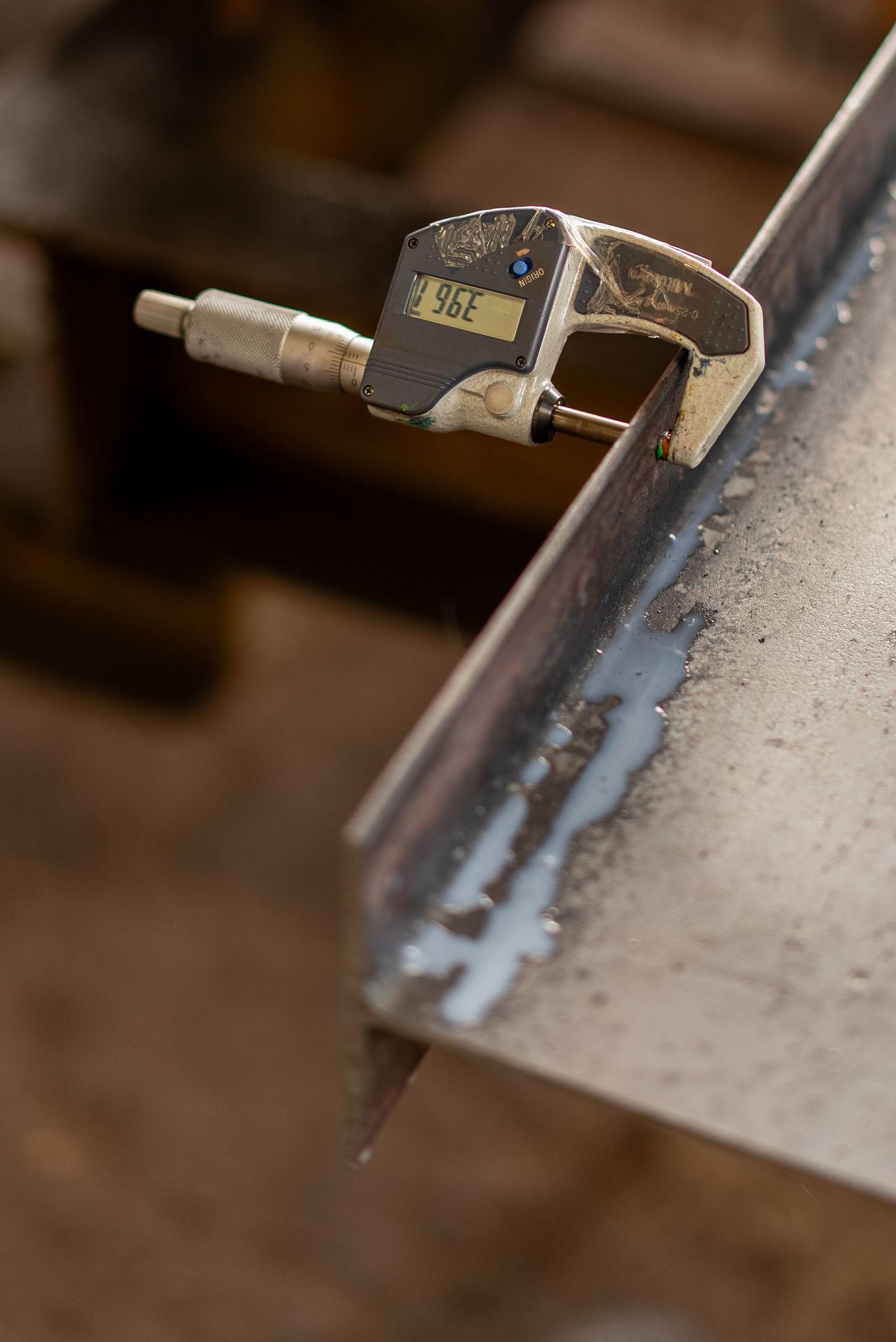 Digital micrometer measuring the thickness of a machined steel edge